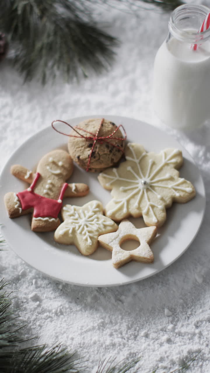 Vertical video of bottle of milk, cookies with copy space on snow background