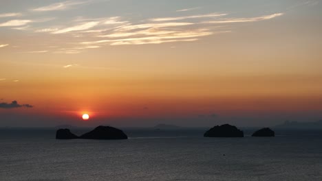 sun down at the horizon behind a group of an islands