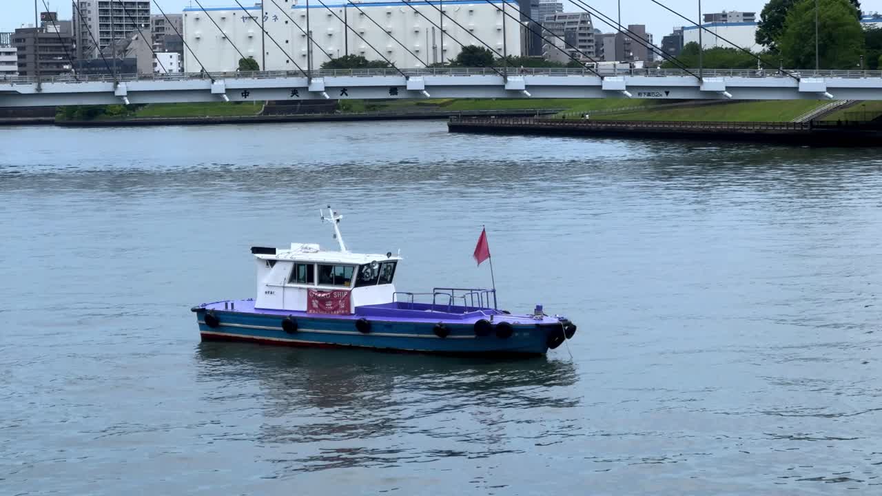 도시 지역 근처의 조용한 강에서 빨간 발을 가진 작은 보트가 떠다닙니다.