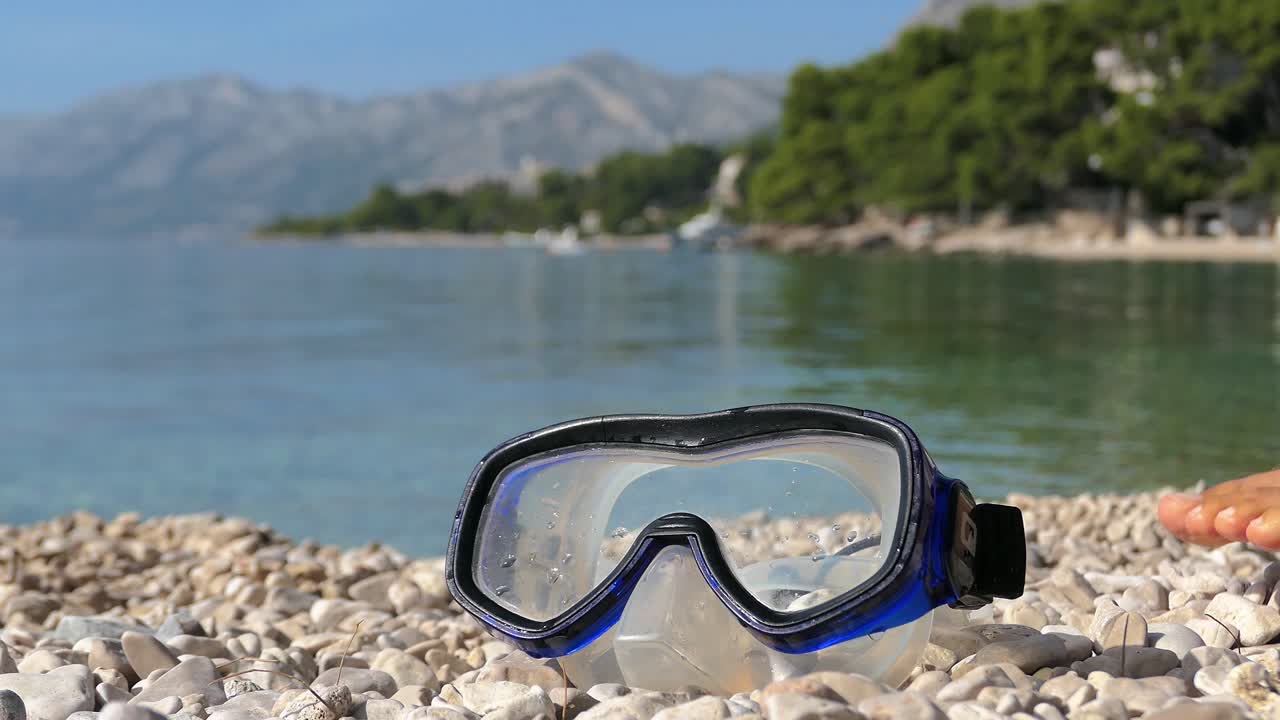 Snorkeler man with fans grabbing snorkeling mask at beach and going into sea