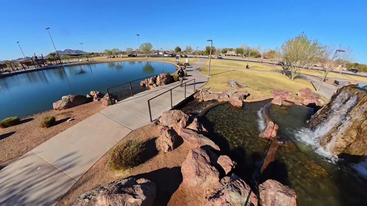 Red haired male walking by fountain Mansel Crater Park in Queen Creek Arizona.