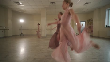 un grupo de jóvenes estudiantes de ballet con ropa de baile negra practicando posiciones en un amplio estudio de ballet con pisos de madera y barras montadas en la pared. expresiones enfocadas y movimientos sincronizados.