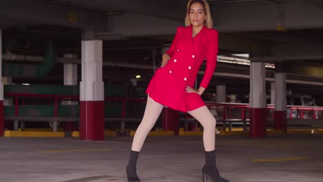 In-the-midst-of-city-life,-a-young-girl-of-Hispanic-origin-graces-a-parking-garage,-dressed-in-a-short-red-attire