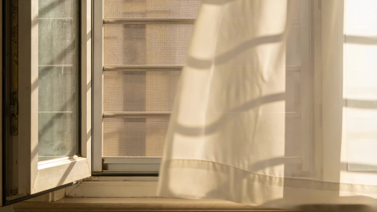 Swaying sheer white curtain billowing from open window in breeze, sunlight casting shadow bands