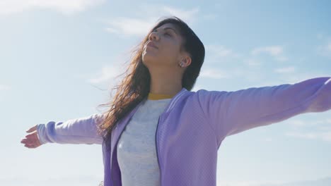 mixed race woman with arms wide at the beach on sunny day