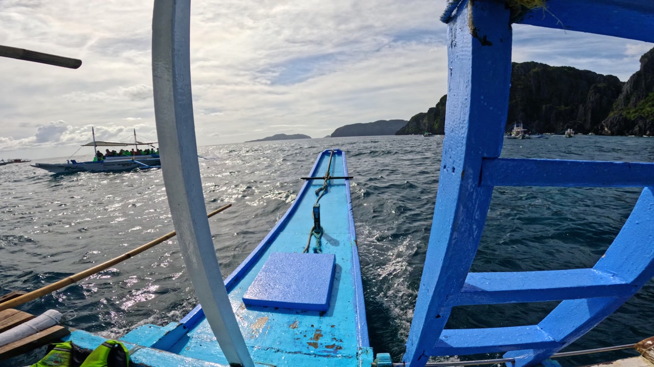 Wide view from boat bow showing island hopping traffic on bright tropical sea