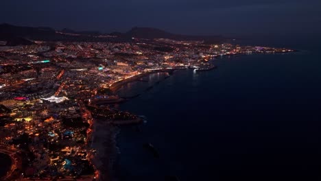 popular vacation destination of costa adeje on island of tenerife, canary islands, aerial view at night tracking right to left.