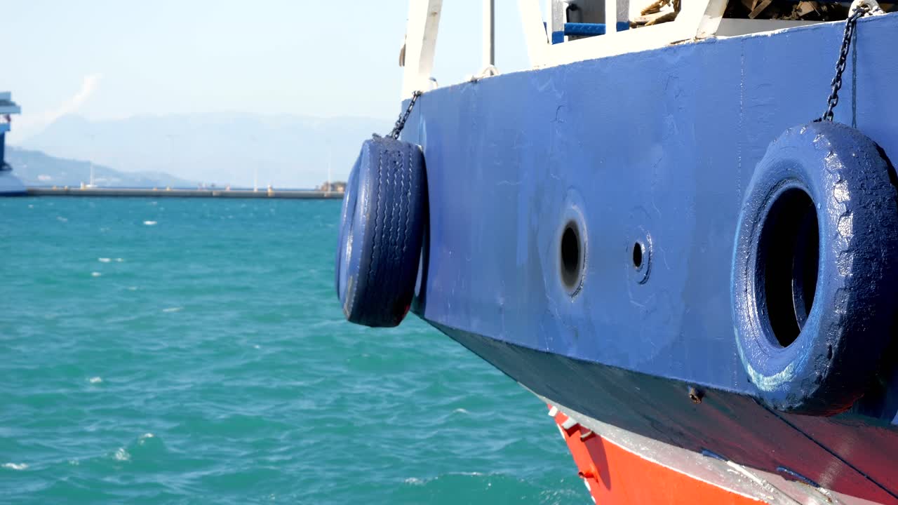 Two blue-painted car tires, attached as bumpers on the ferry's sides