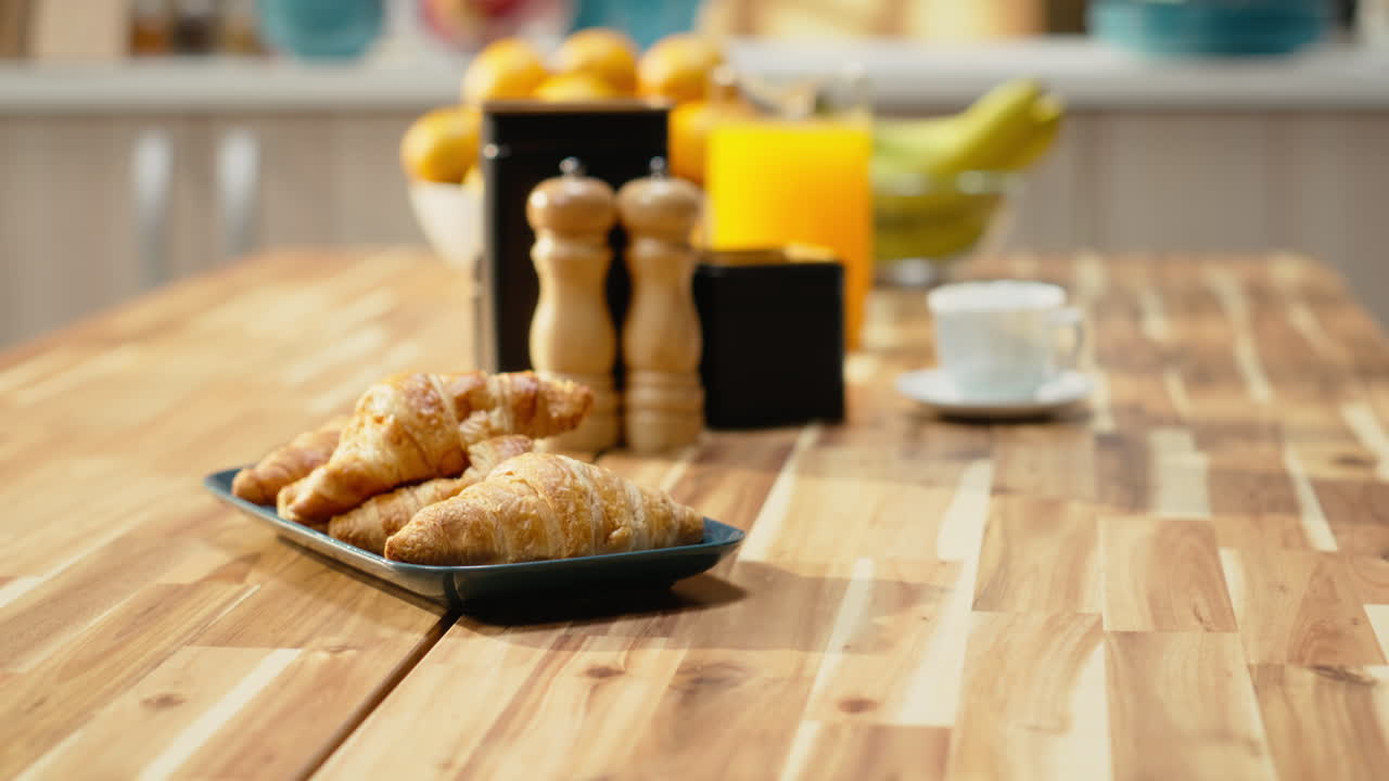 Kitchen with wooden breakfast table with pastry and fruits in empty home