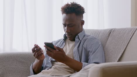 hombre usando un teléfono inteligente en un sofá