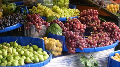 primer plano de un puesto de frutas con uvas, albaricoques y peras