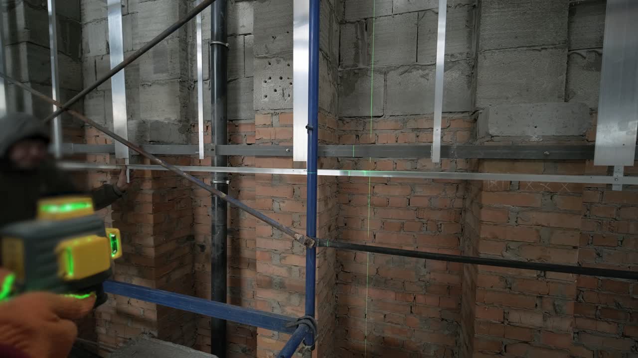 el constructor mide las líneas de reparación utilizando un nivel de láser verde