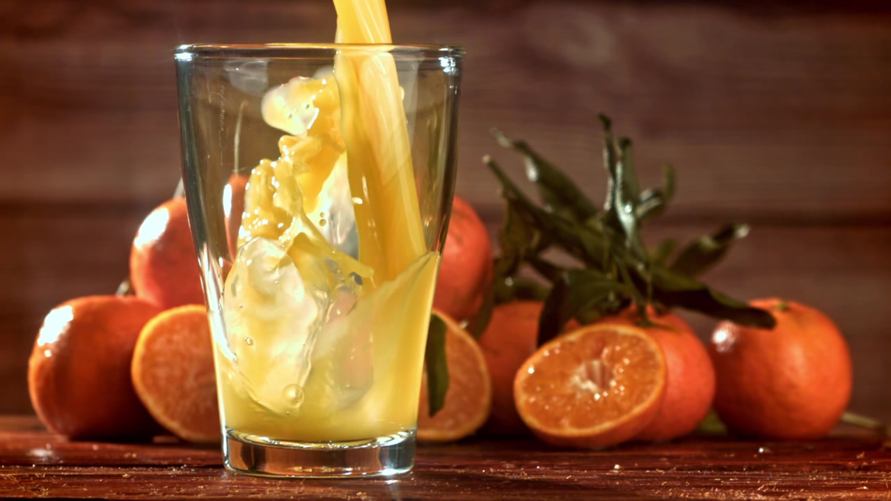 Fresh Orange Juice Pouring into a Glass with Tangerines