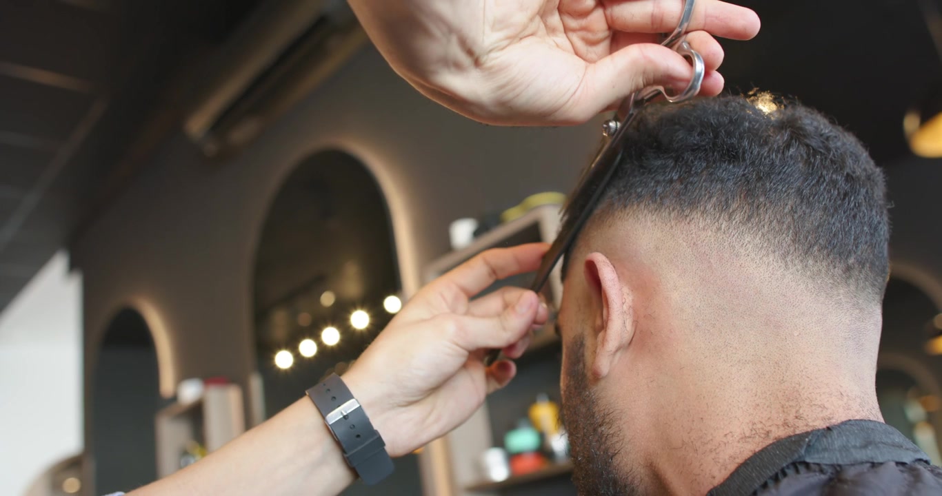 Barbiere Afroamericano che Usa Pettine e Forbici per Tagliare i Capelli del Cliente in Negozio, Sfumatura Vicino all'Orecchio