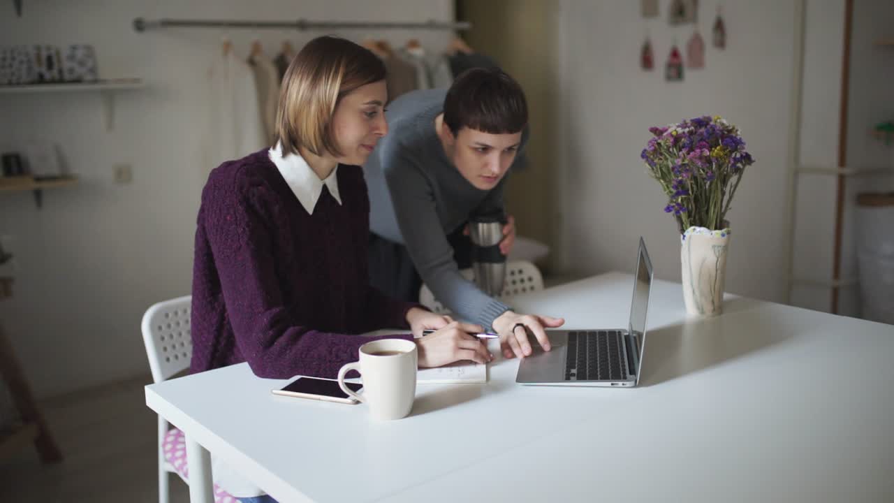 Mujer joven sentada en una mesa y escribiendo en el teclado de un portátil. Portátil de amigas.
