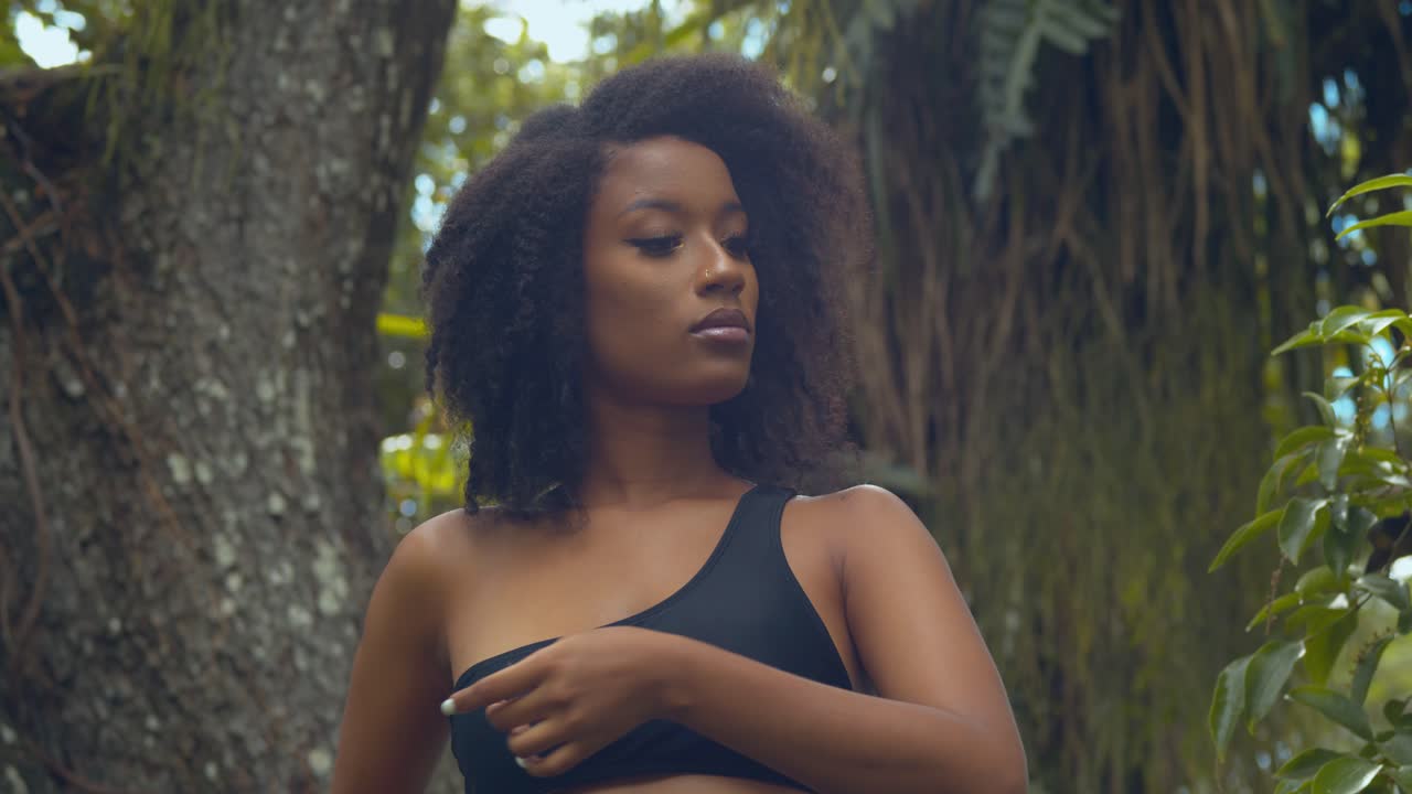 A young natural hair model walks down the tree trunk of a large silk cotton tree
