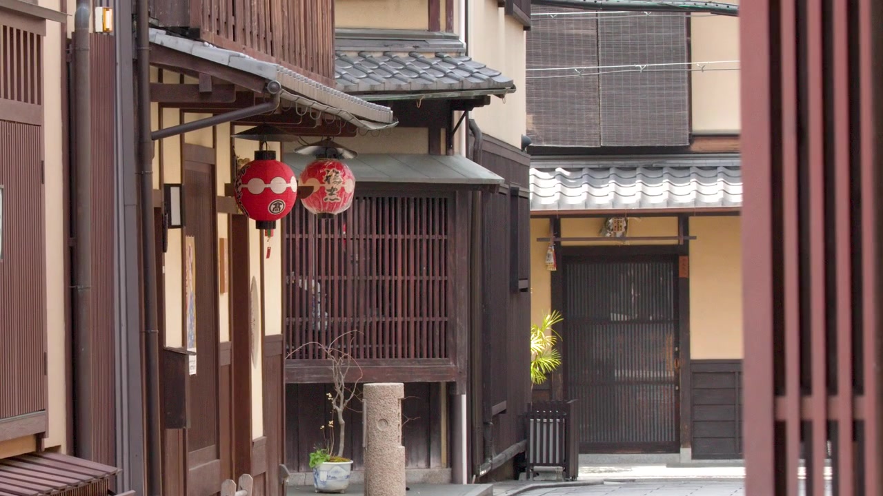 Inquadratura statica di una tranquilla strada di Kyoto con tradizionali edifici in legno e lanterne di carta rosse