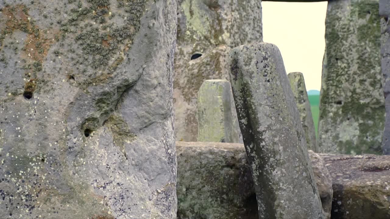 Detailed macro view of lichen-covered sarsen stones at Stonehenge near Salisbury, England, showing erosion marks, boreholes, and prehistoric stone texture.