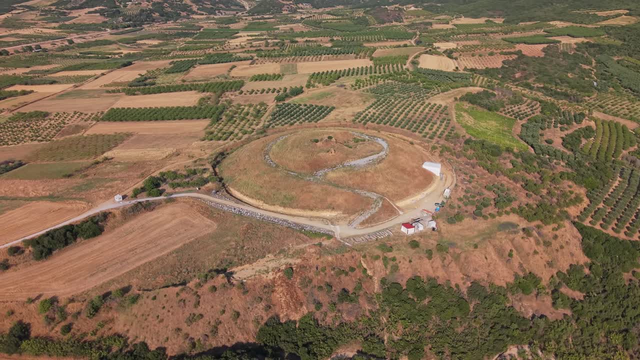 Drone orbiting the huge Amphipolis Tomb in Macedonia, Greece. Majestic aerial view highlighting the ancient monument and surrounding landscape