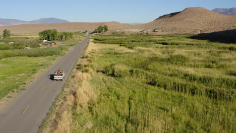 Weißes-Auto-Bewegt-Sich-Auf-Einer-Straße-Mit-Einer-Wunderschönen-Landschaft-Und-Einem-Grünen-Feld