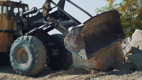 An old bulldozer at a quarry transports a large stone block. Excavator work in the mining industry