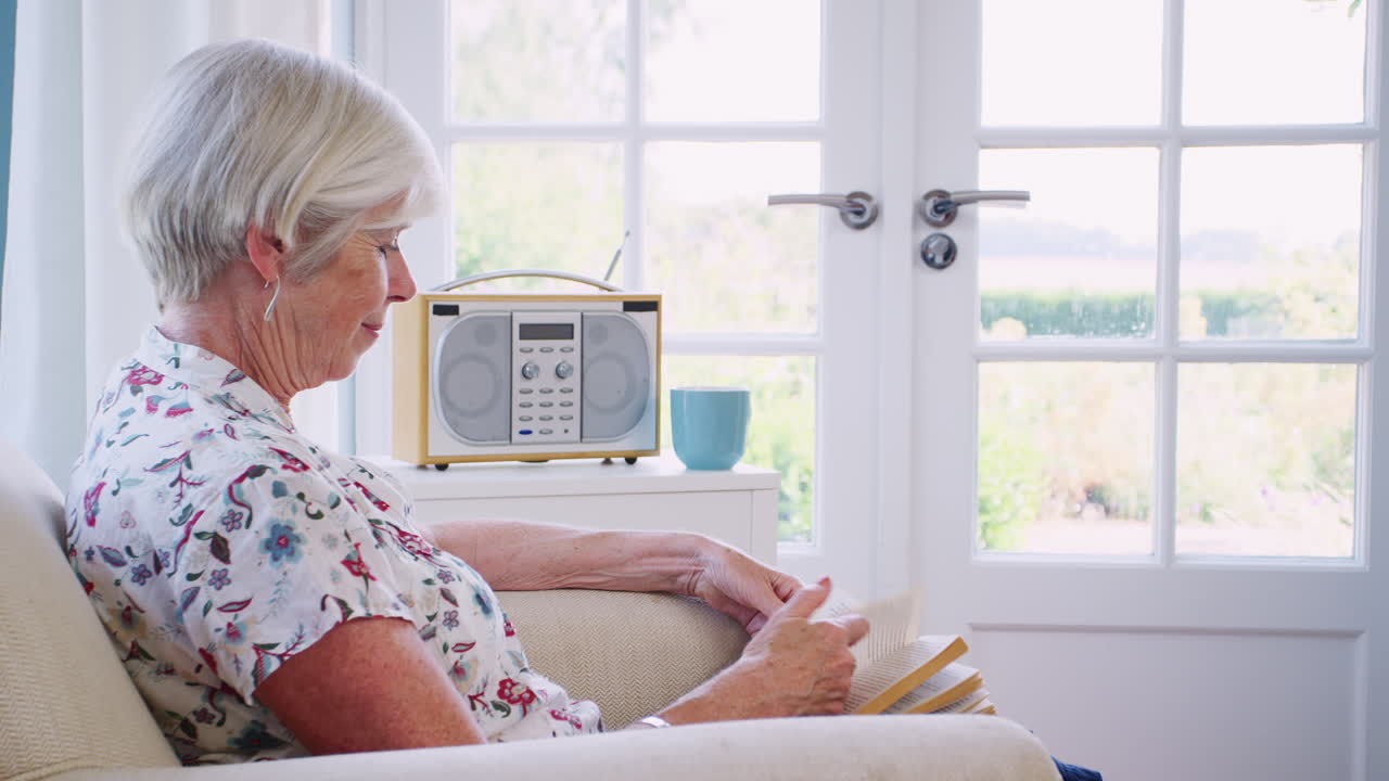 집 에서 책 을 읽고 의자 에 앉아 있는 고위 여성