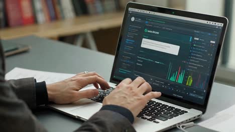 financial analyst working on a laptop with a stock market data dashboard