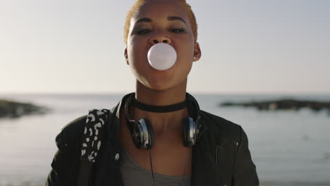 retrato de una joven feliz mujer afroamericana soplando chicle divirtiéndose en la playa