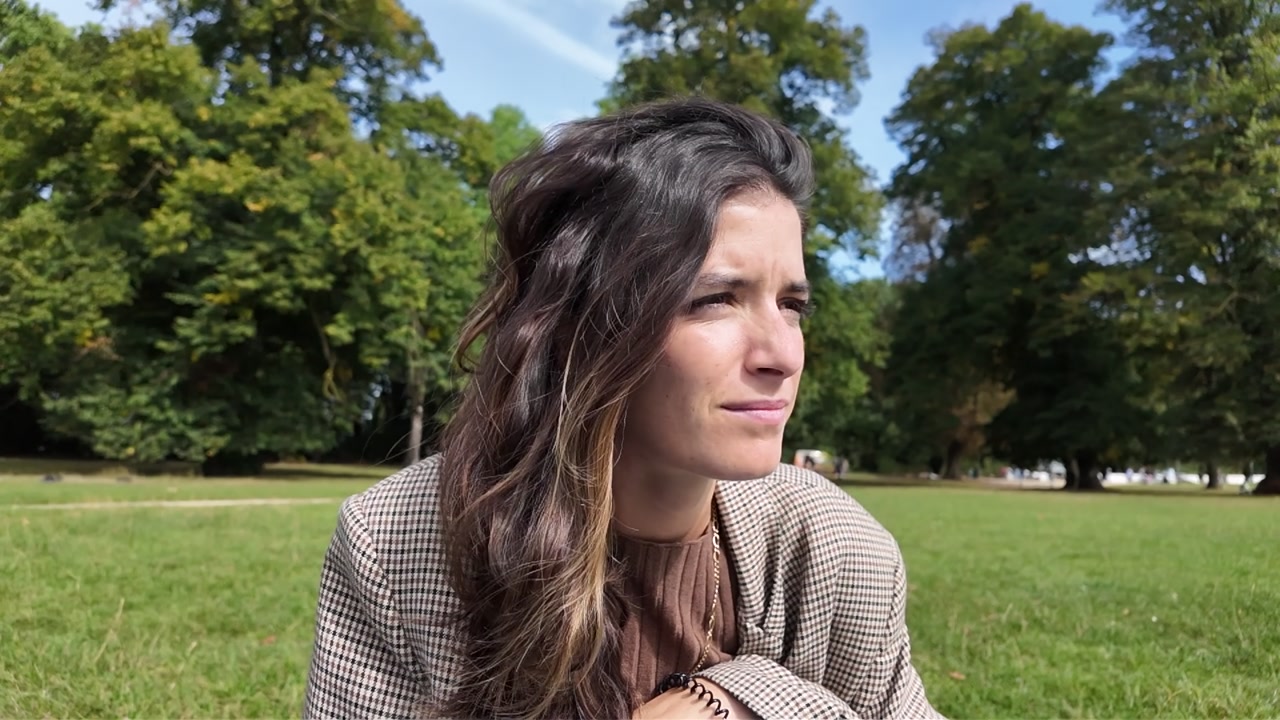 Slow motion of woman with hair blowing in the wind while sitting in park