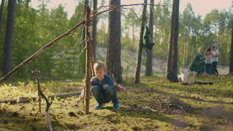 family trip in picturesque forest at summer married couple is pitching tent and little boy is playing