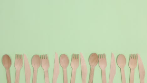 eco friendly zero waste kitchen utensils cutlery move left right on bottom of light green background. stop motion