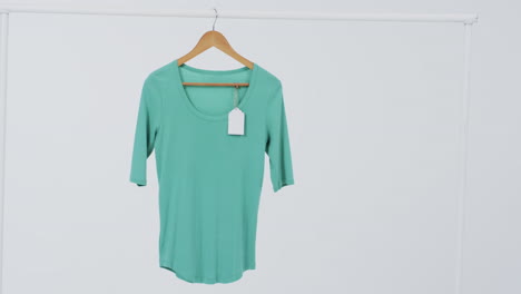 video de camiseta verde con etiqueta en el colgador y espacio de copia en fondo blanco