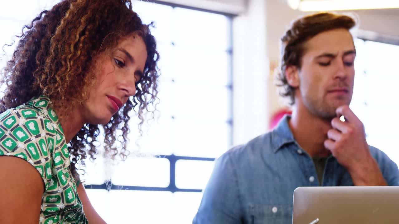 mujer usando su teléfono mientras trabaja con un colega