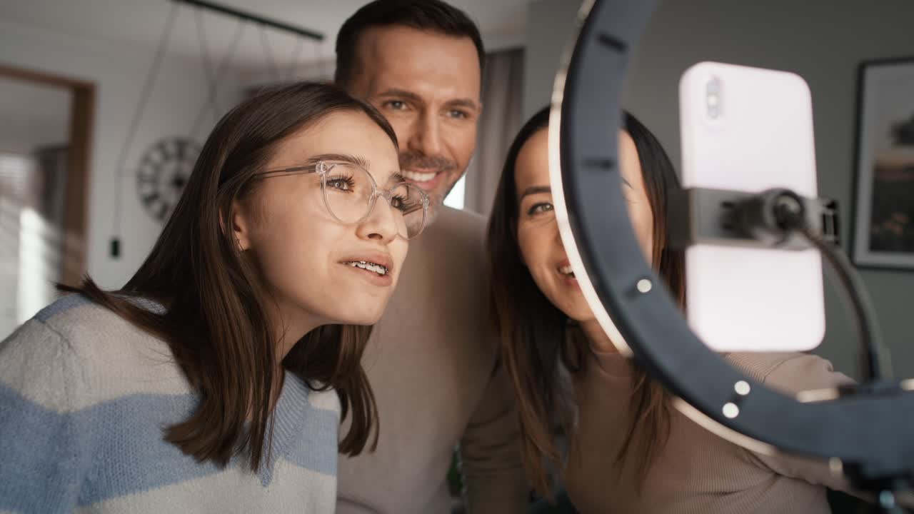 niña adolescente con padres comprobando el baile grabado para las redes sociales usando teléfono móvil