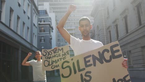 Two-mixed-race-men-on-a-protest-march-holding-placards-raising-hands-and-shouting