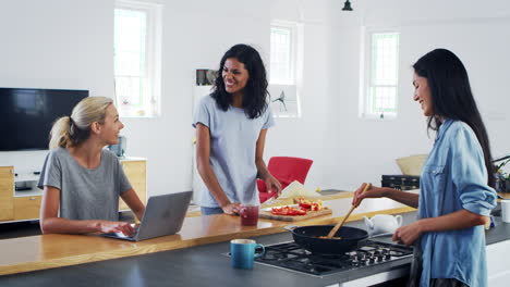 three female friends preparing meal together in modern kitchen