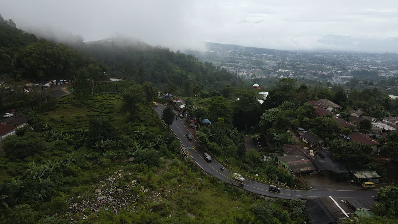 Vehículos circulando por carretera de montaña cerca de Puncak en Java Occidental, Indonesia