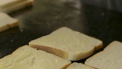 mujer joven ocupada untando pan con mantequilla para hacer sándwiches a la barbacoa para el almuerzo