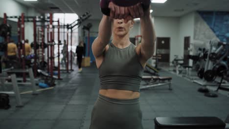 Young-caucasian-woman--exercising-with-kettlebells-at-a-gym.