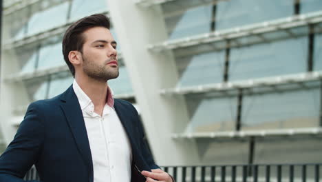 portrait businessman walking outdoors. man looking away outdoors at city