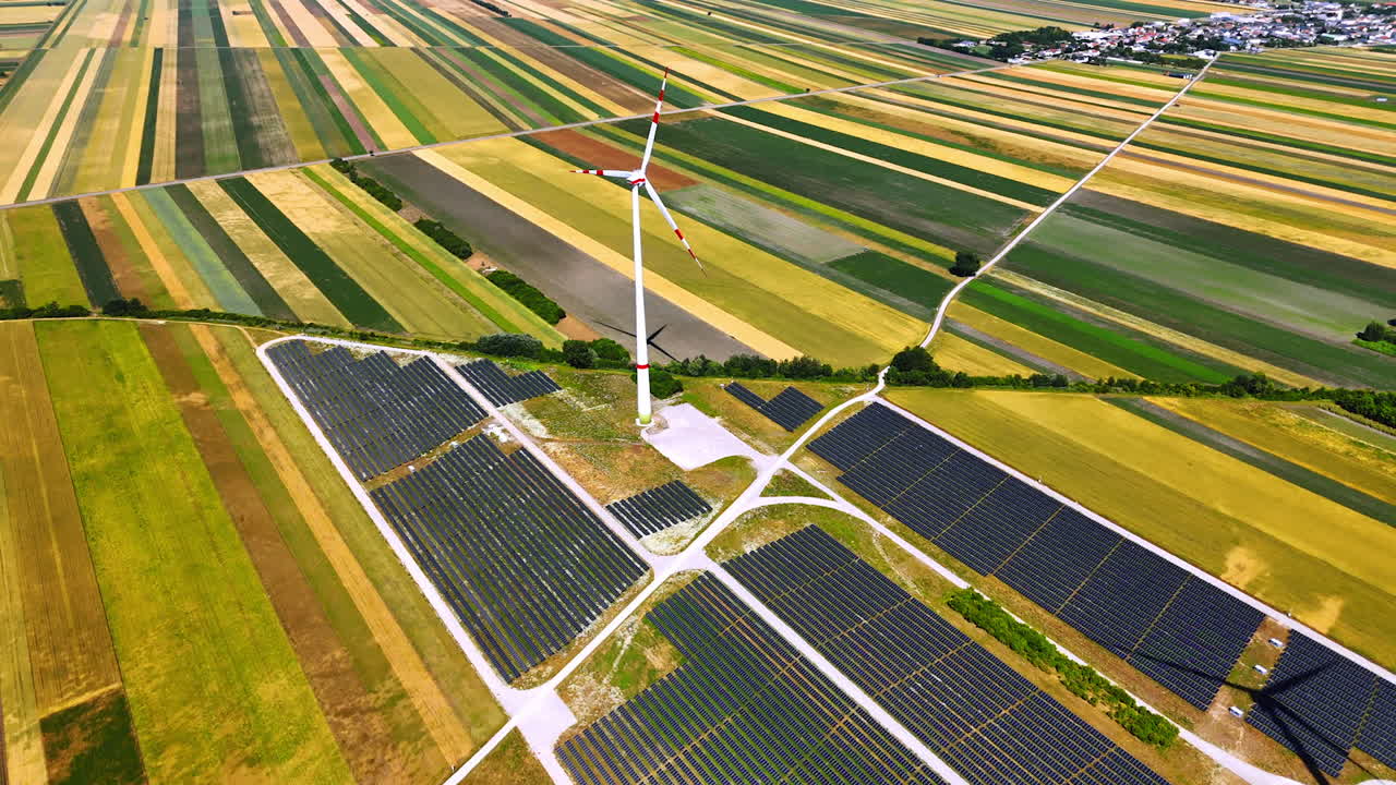 Amazing striped agricultural plantations in the countryside. Wind mills rotate in the wind over the fields with solar panels