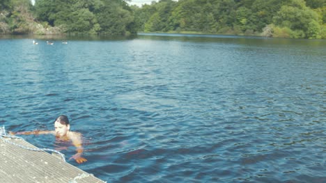 un joven se relaja nadando en un río natural