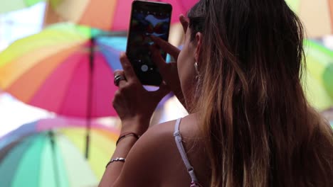 chica tomando fotos de sombrillas de colores de cerca