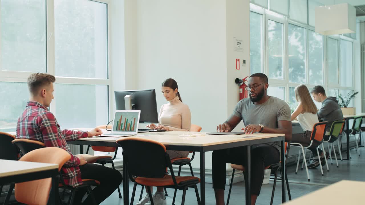 Black man finishing work in coworking space. Serious man closing laptop computer