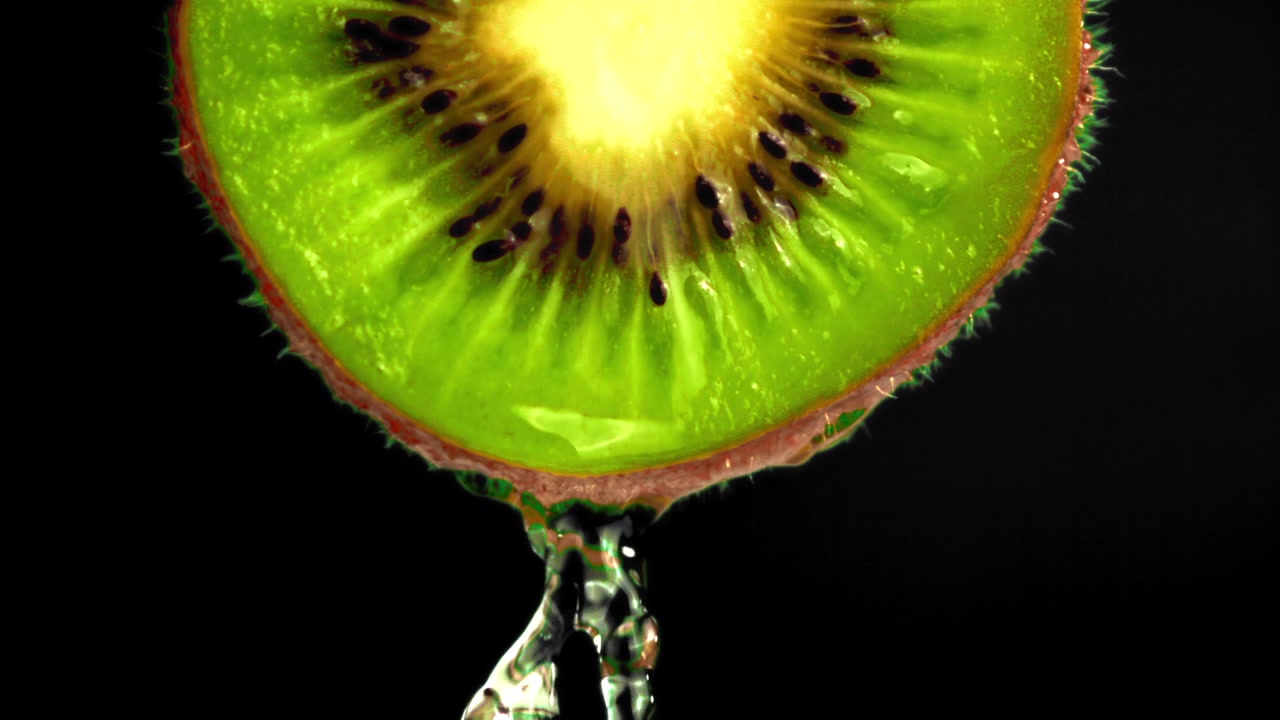 Wassertropfen von einer frischen Kiwischeibe auf schwarzem Hintergrund.