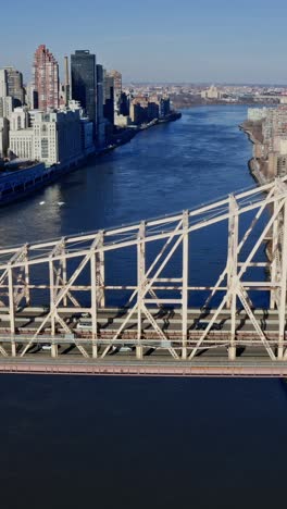 east river amidst buildings in city, drone flying backward from skyline