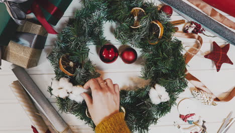 vista superior de la corona de navidad sobre fondo artesanal, bonita mano de mujer decorando la corona de navidad, toma de movimiento