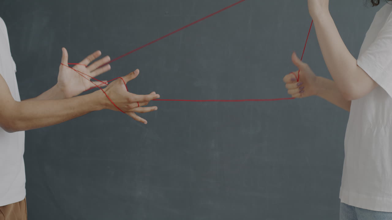 Two People Playing with Red Strings