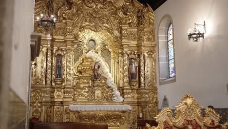 golden baroque altar with statues and white floral garland