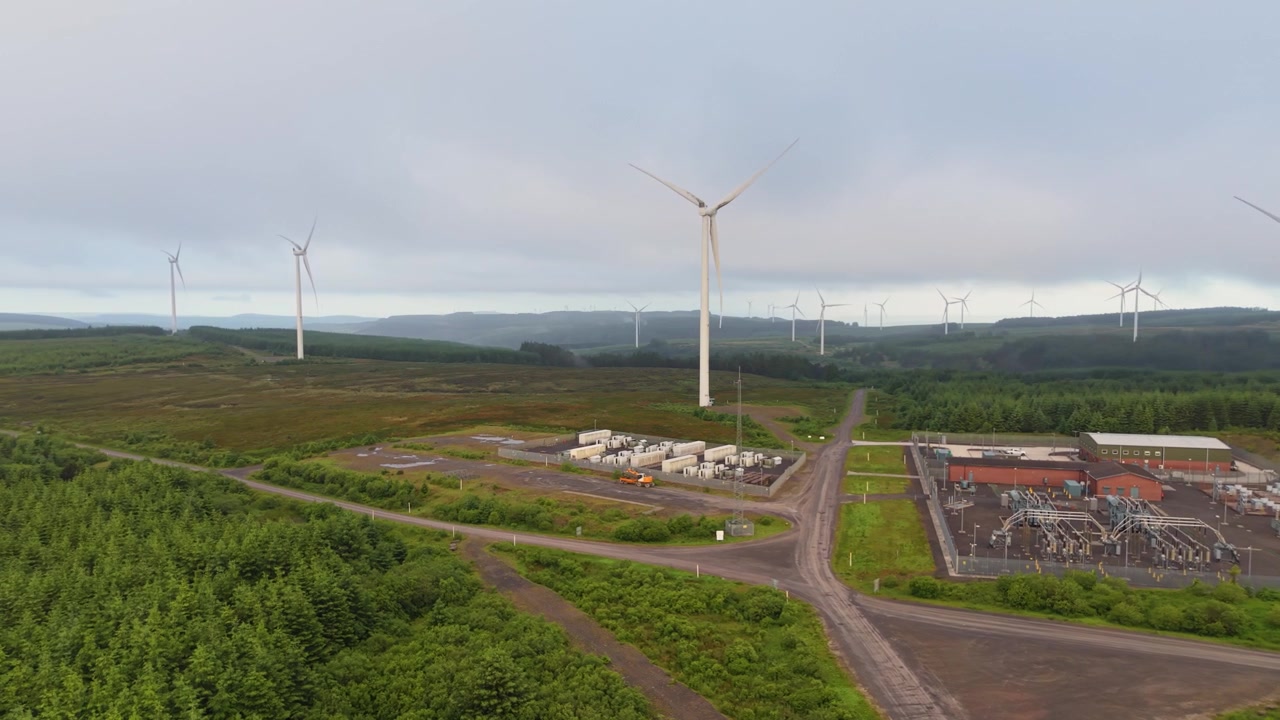 Landscape Aerial of Wind Farm with Modern BESS Battery Storage System and Substation. Showing Natural Land Integrated with Modern Renewable Technology.